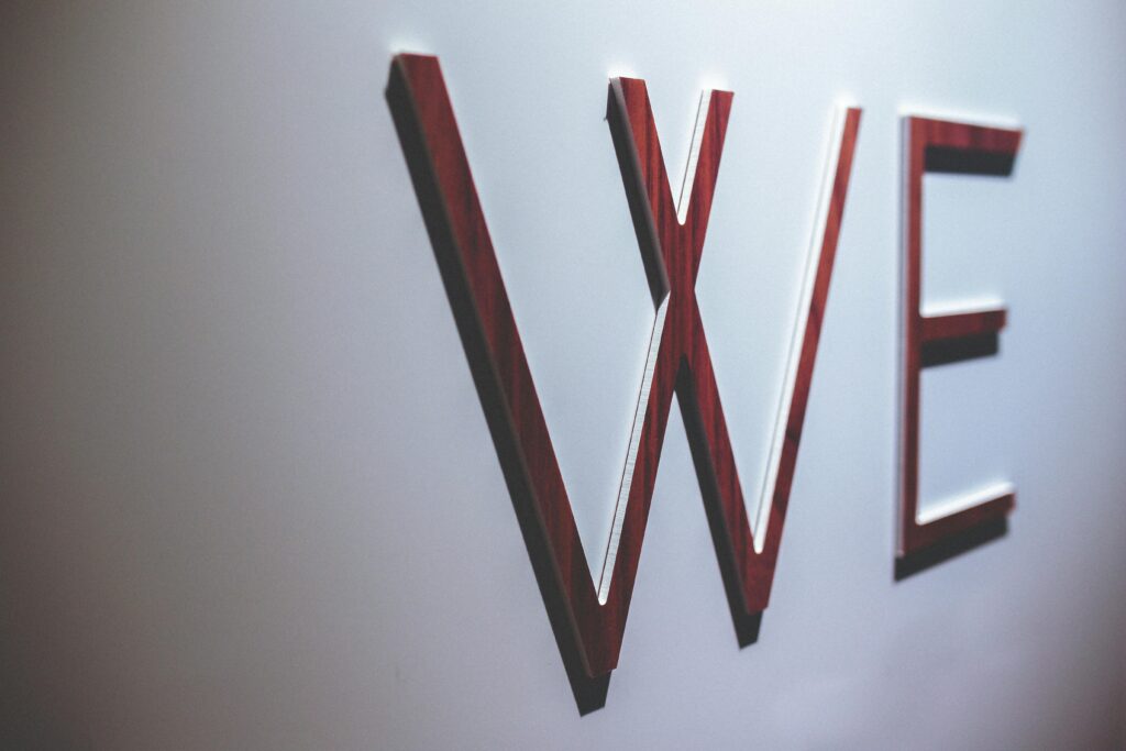 Abstract image depicting wooden letters spelling 'WE' on a white wall.